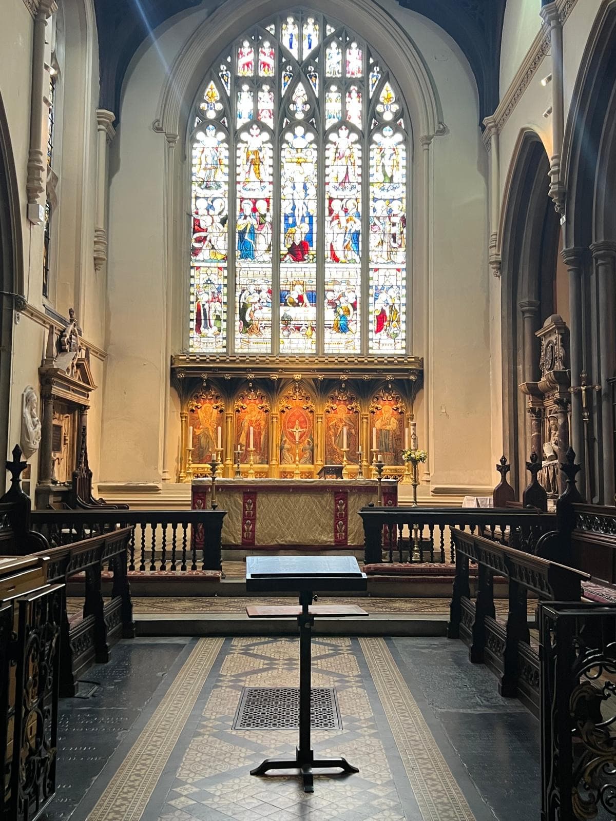 Chancel of All Saints Church, Fulham, with a large stained-glass window above a gilded altar